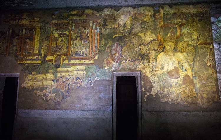 Interior of an Ajanta cave with painted walls and a dark shrine doorway